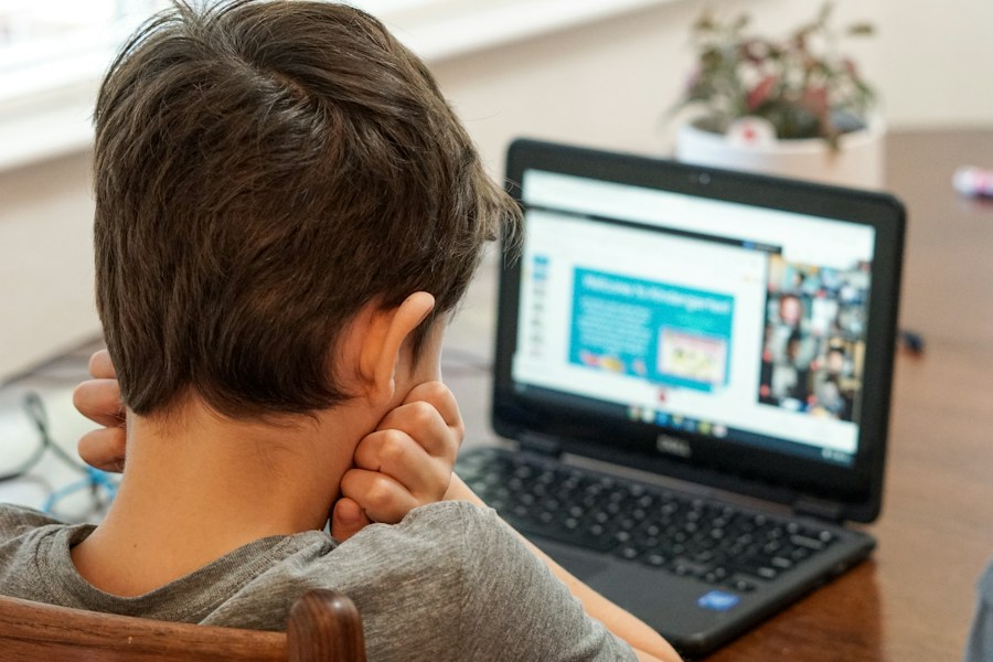 A school student following an online lesson on his laptop at home