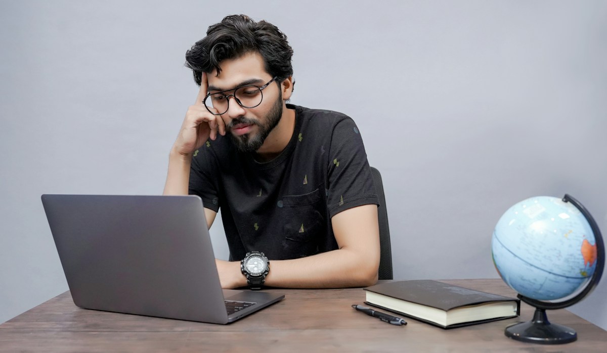 A college student studying on his laptop at a desk