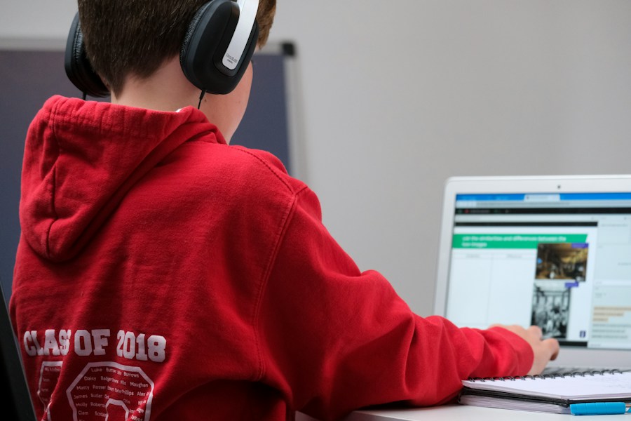 A student wearing headphones attending an online class on a laptop