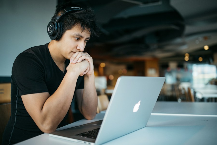 A learner with headphones focused on an online class on his laptop
